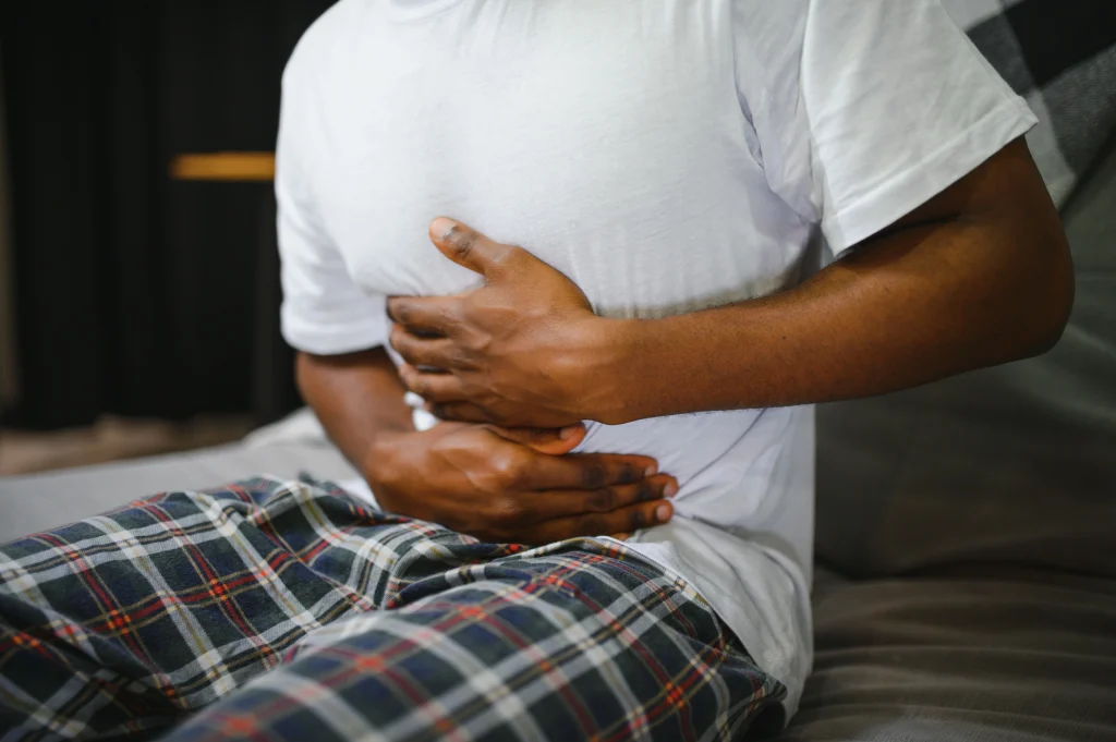 A man in Katy, TX clutching his stomach due to abdominal pain, possibly from food poisoning or a stomach bug—ER Katy provides 24/7 emergency care.