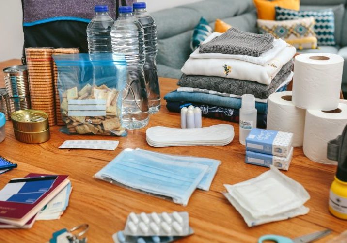 Emergency preparedness supplies for hurricane season in Katy, TX, including bottled water, non-perishable food, face masks, medications, hygiene products, clothing, and important documents arranged on a table.